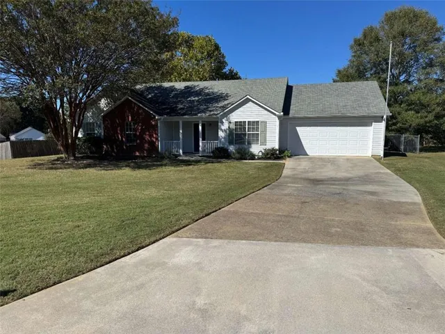 a front view of a house with a garden and trees