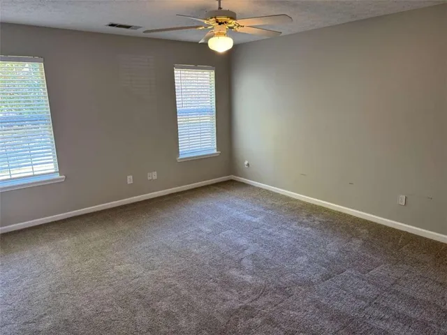 an empty room with windows and fan