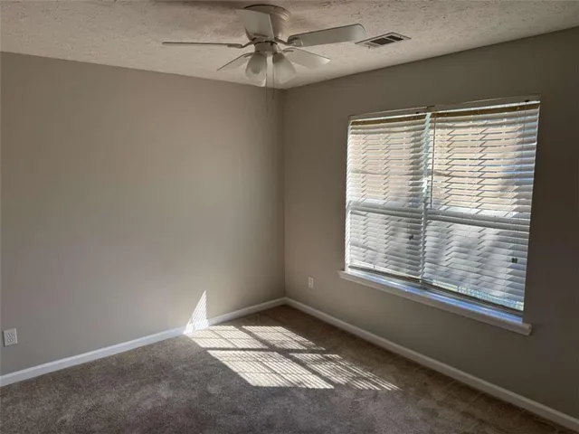 an empty room with a window and a fan