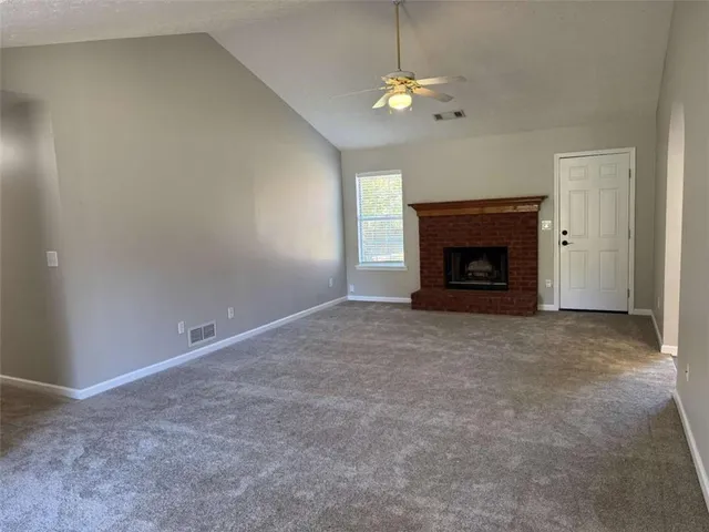 an empty room with a fireplace and chandelier fan