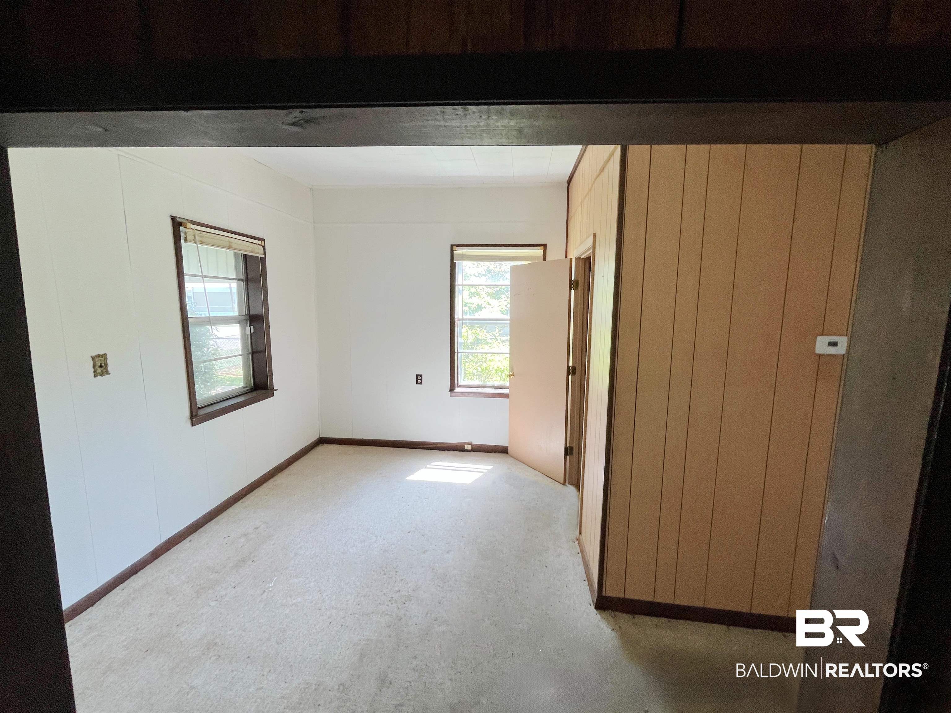 215 Adams Street Atmore, AL 36502 - Photo 4 of 7 Empty room with wood walls and beam ceiling