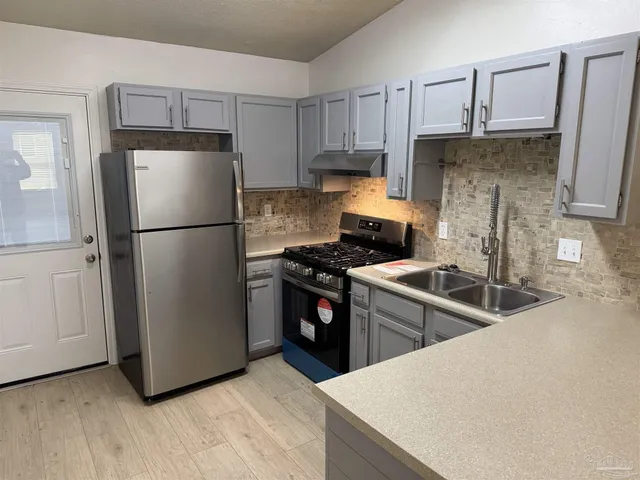 a kitchen with stainless steel appliances granite countertop a refrigerator stove a sink and dishwasher