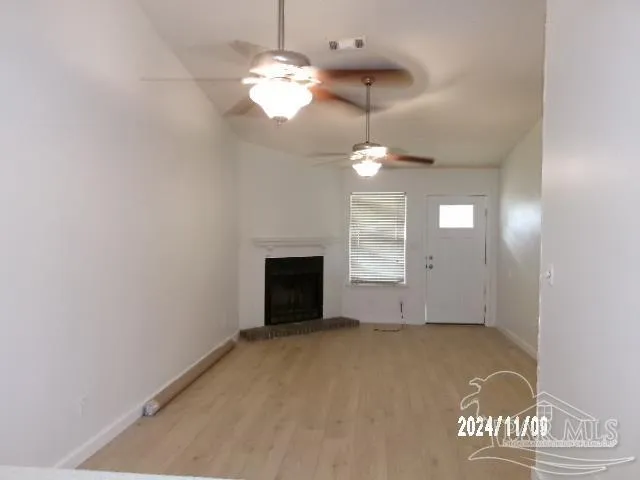 an empty room with a fireplace and chandelier fan
