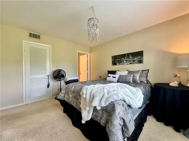 a spacious bedroom with a bed and a chandelier