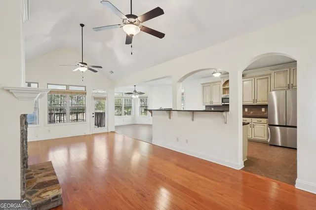 a view of an empty room with kitchen and window