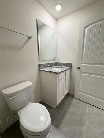 a bathroom with a granite countertop toilet sink and mirror