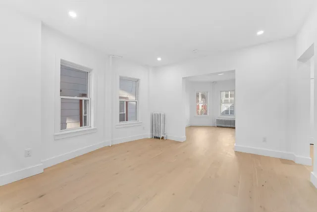 a view of empty room with wooden floor and windows