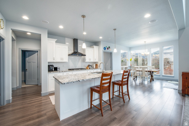 262 North Santa Fe Drive Mapleton, UT 84664 - Photo 12 of 28 Kitchen with light stone counters, white cabinets, dark wood-style floors, a center island with sink, and a kitchen breakfast bar