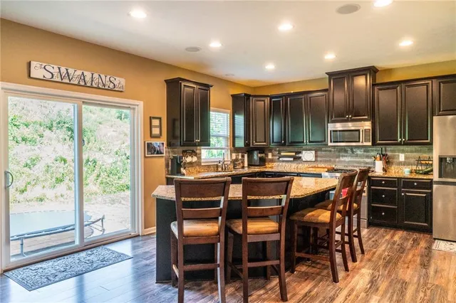 a kitchen with kitchen island granite countertop wooden cabinets and stainless steel appliances