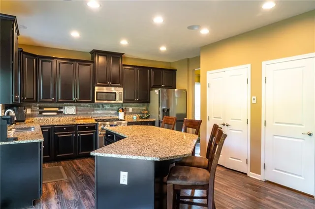 a kitchen with kitchen island a stove a sink a refrigerator with a dining table and chairs