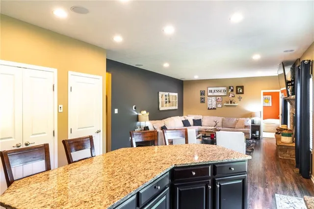 a living room with stainless steel appliances granite countertop furniture wooden floor and a large window