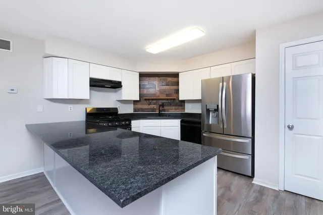 a kitchen with a refrigerator a microwave a sink and cabinets