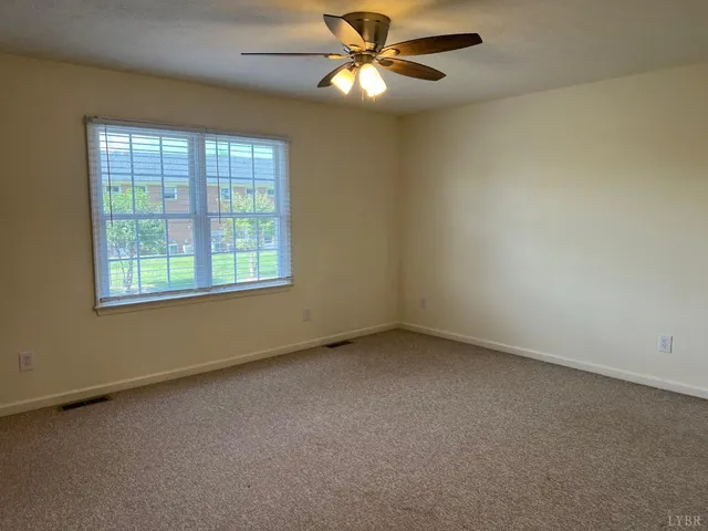 an empty room with a window and a fan