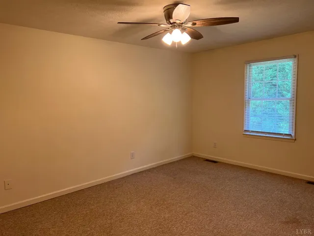 an empty room with a window and a fan