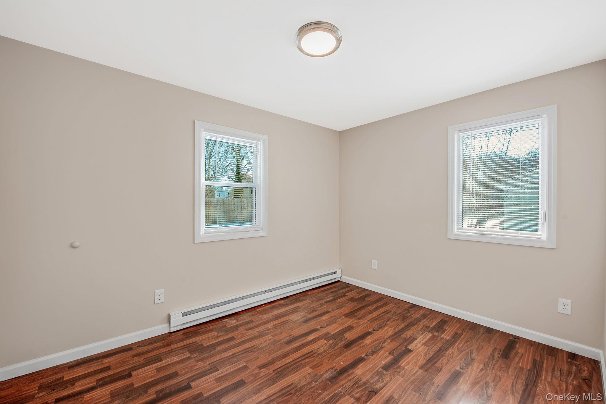 703 Provost Avenue Bellport, NY 11713 - Photo 14 of 16 an empty room with wooden floor and windows