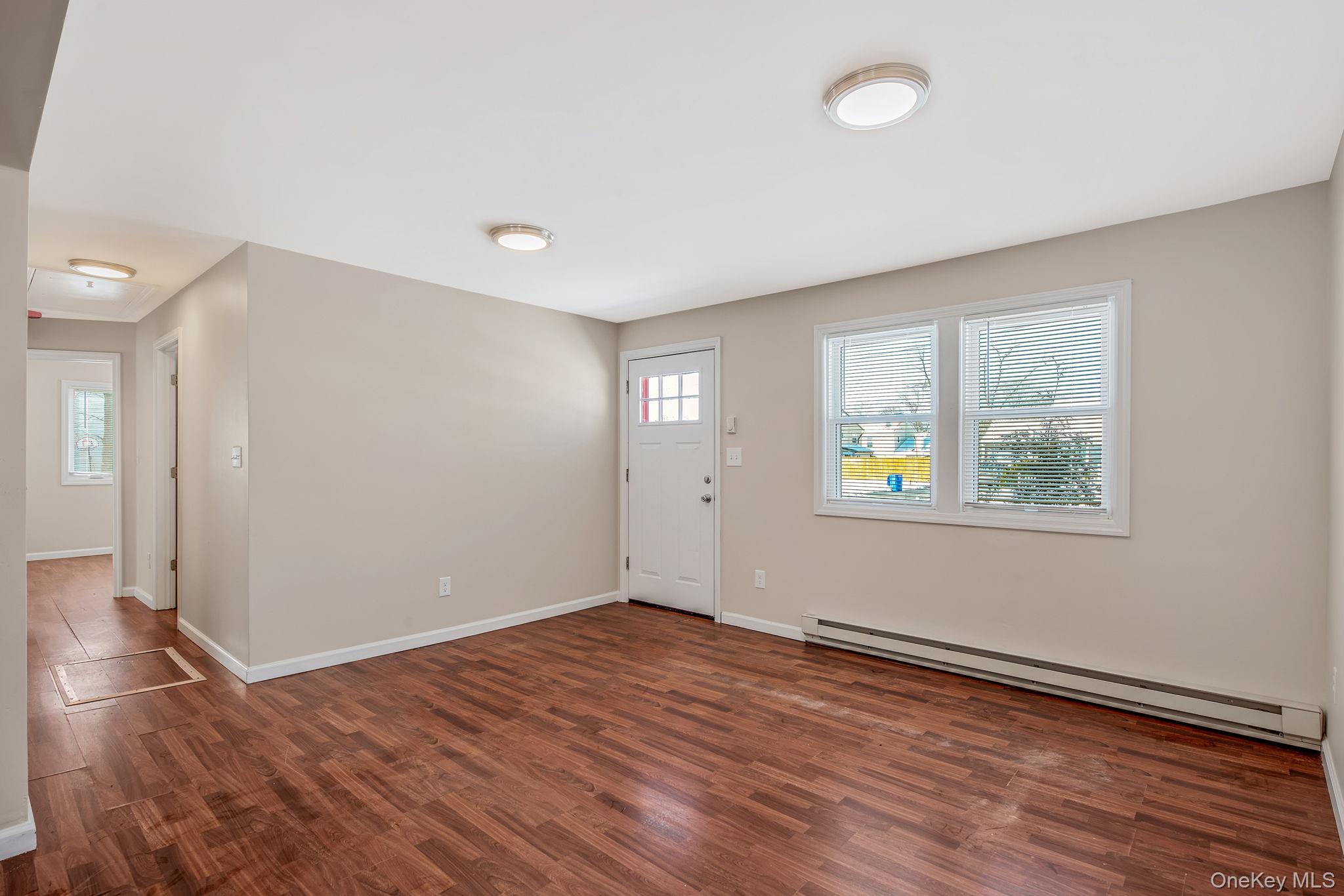 703 Provost Avenue Bellport, NY 11713 - Photo 3 of 16 wooden floor in an empty room with a window