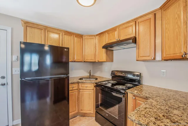 a kitchen with stainless steel appliances granite countertop a refrigerator a stove and a sink with wooden floor