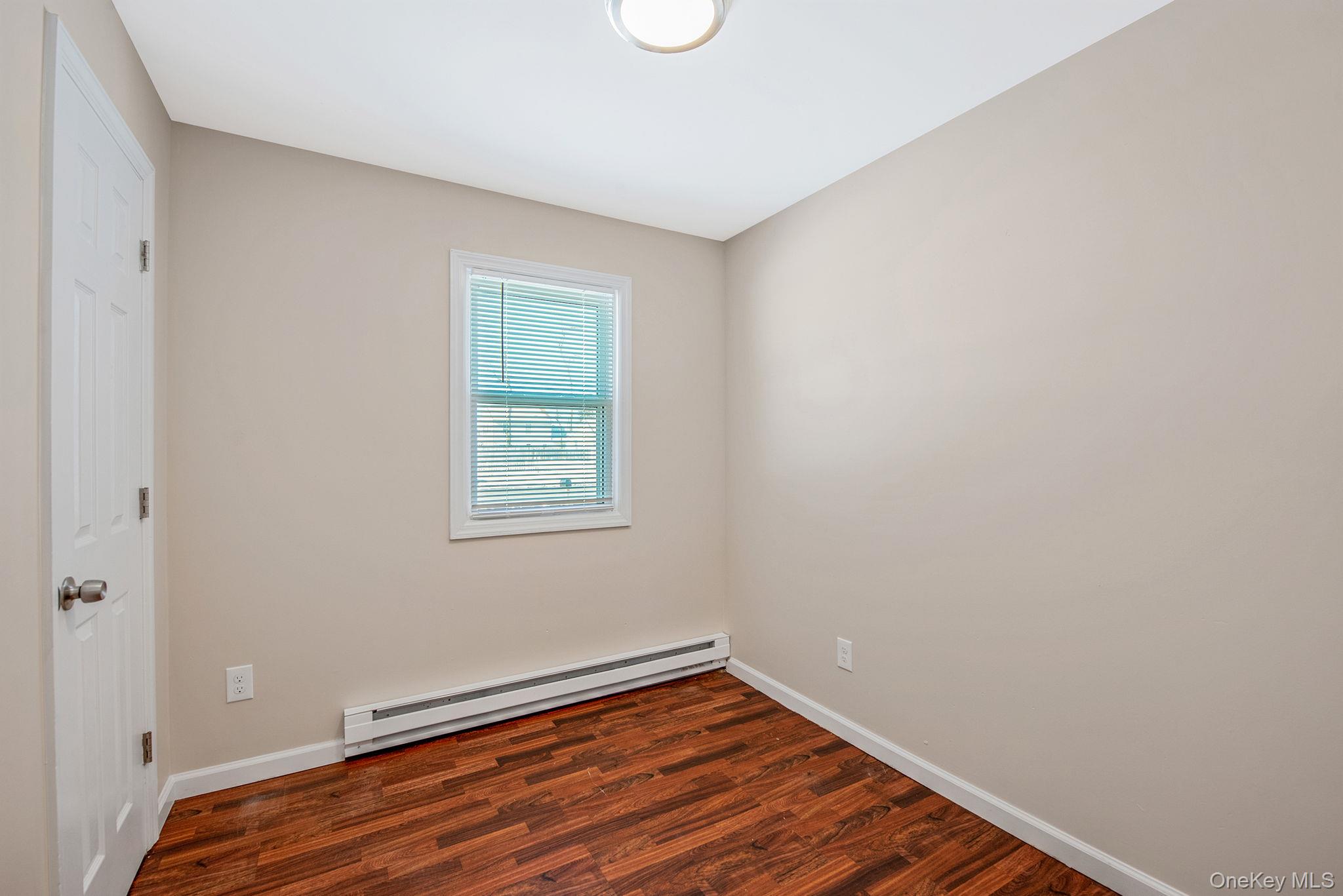 703 Provost Avenue Bellport, NY 11713 - Photo 10 of 16 a view of an empty room with wooden floor and a window
