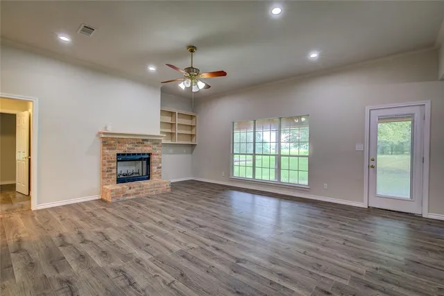 an empty room with wooden floor fireplace and window