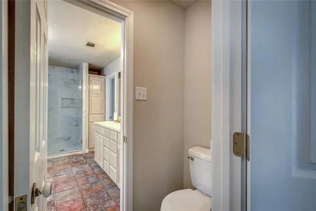 a bathroom with a granite countertop toilet and a shower