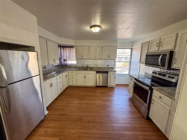 a kitchen with granite countertop a refrigerator stove top oven and sink