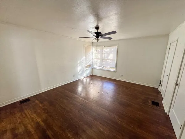 an empty room with wooden floor fan and windows