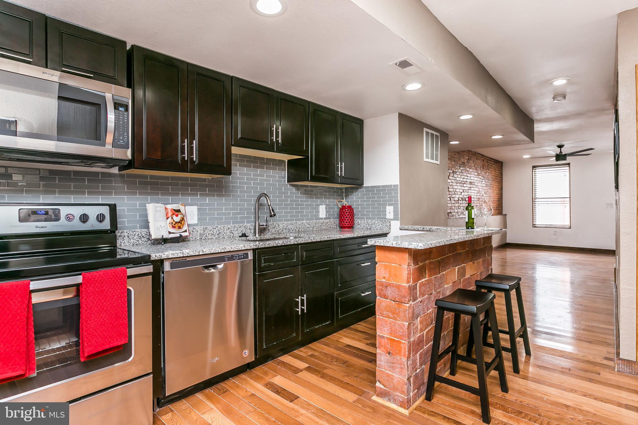 609 Wyeth Street Baltimore, MD 21230 - Photo 1 of 32 a kitchen with stainless steel appliances granite countertop wooden cabinets a sink dishwasher and a stove top oven with wooden floor
