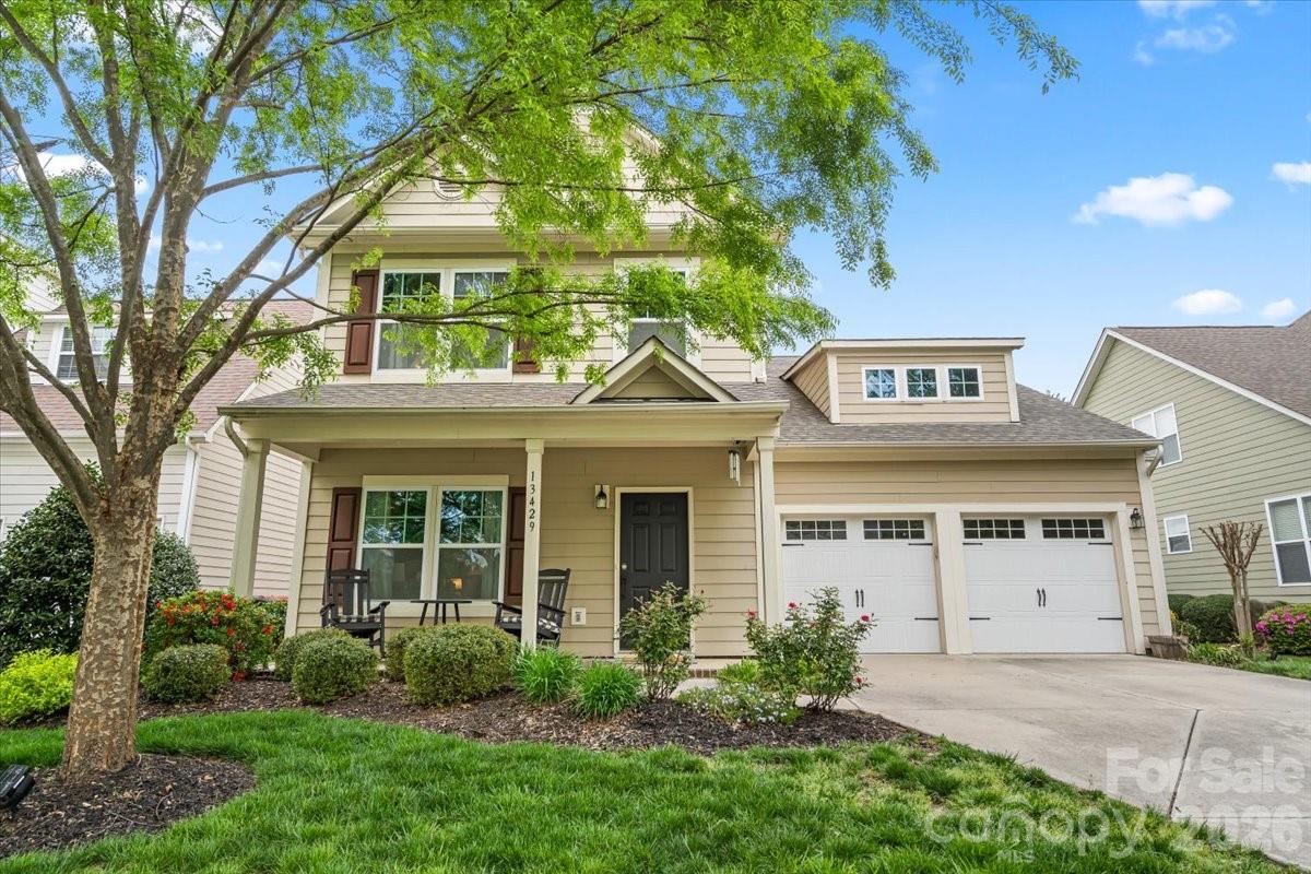a view of a white house next to a yard with plants and trees