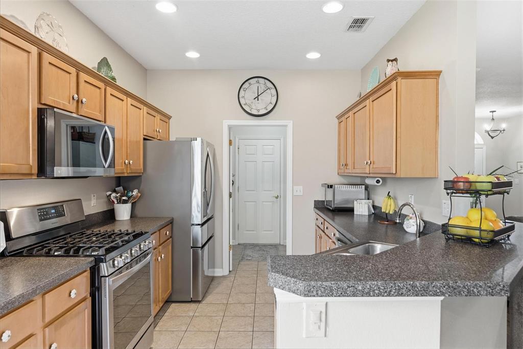 207 Coleton Lane DeLand, FL 32724 - Photo 22 of 65 a kitchen with stainless steel appliances granite countertop a stove top oven a refrigerator a sink and dishwasher with wooden floor