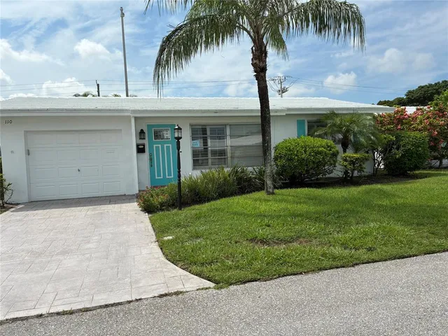 front view of house with a yard and palm trees
