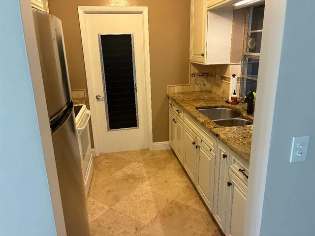 a kitchen with a sink a refrigerator and cabinets