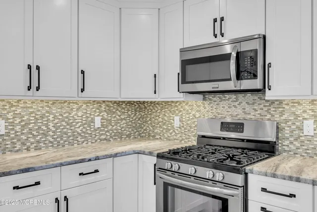 a kitchen with granite countertop a stove top oven microwave and cabinets