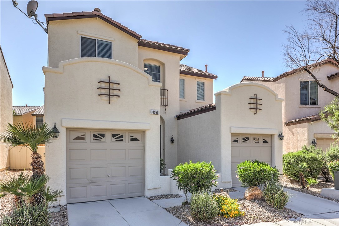 10939 Paradise Road Henderson, NV 89052 - Photo 2 of 36 A cream-colored stucco exterior with a tiled roof, inviting a bright and airy ambiance.