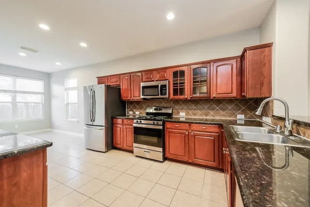 a kitchen with stainless steel appliances granite countertop a refrigerator stove and sink