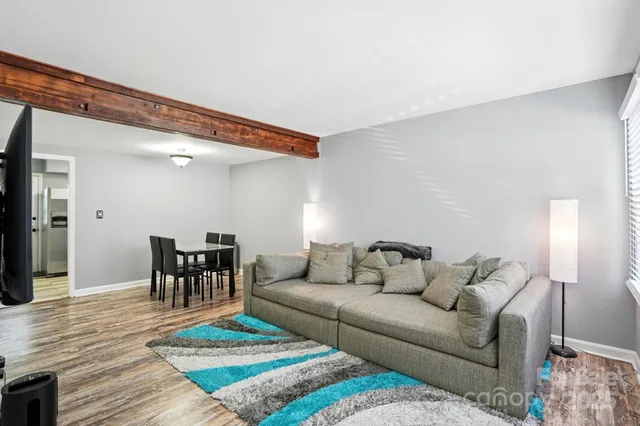 a living room with furniture and a dining table with wooden floor