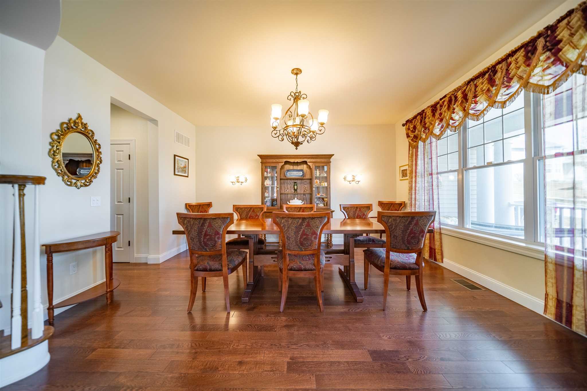 a dining room with wooden floor a chandelier a glass table and chairs