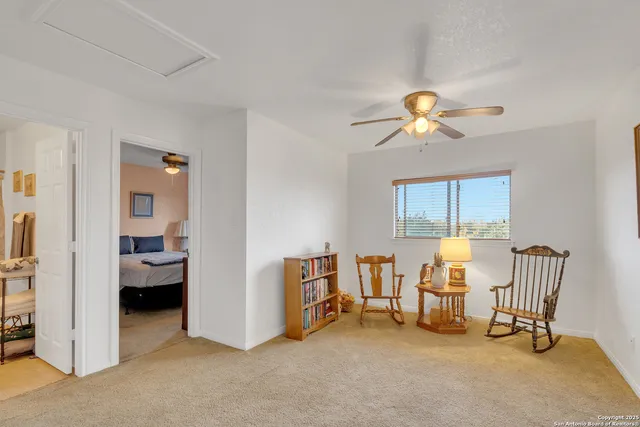 a view of a livingroom with lounge chair and a ceiling fan