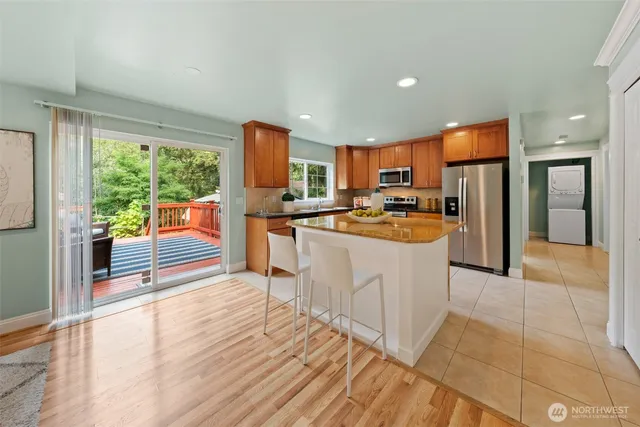 a kitchen with stainless steel appliances a stove a refrigerator a sink a oven and a dining table with wooden floor
