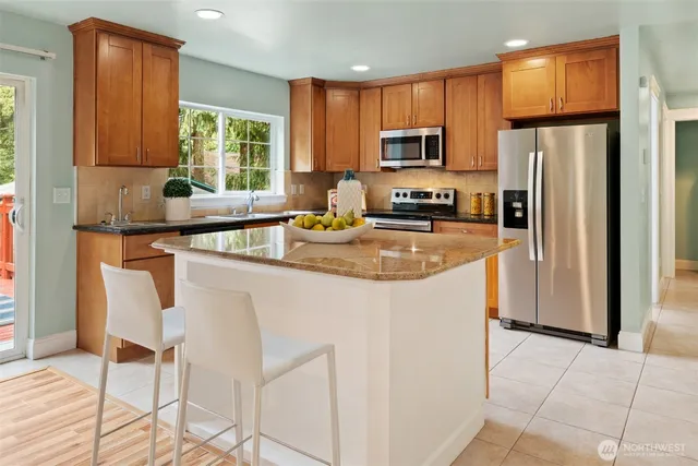 a kitchen with stainless steel appliances granite countertop a refrigerator a stove a sink a dining table and chairs