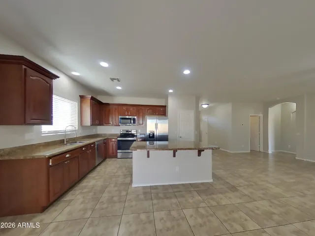 a large kitchen with stainless steel appliances granite countertop a stove a sink and a refrigerator