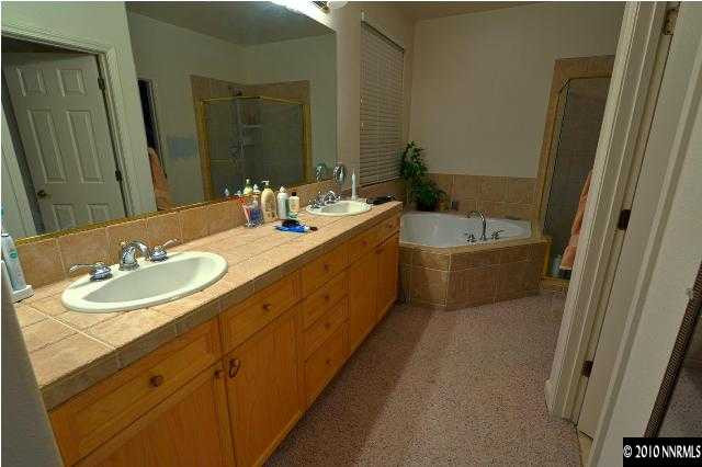 1730 Ornellaia Way Reno, NV 89521 - Photo 10 of 12 a bathroom with a double vanity sink a mirror and a bathtub