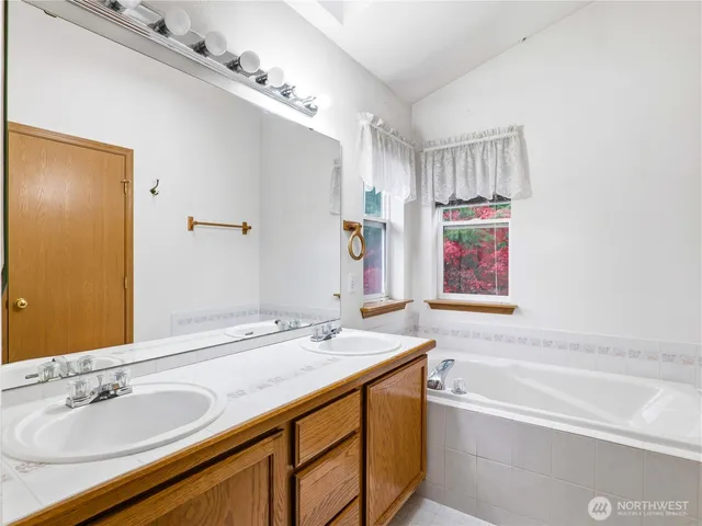 a bathroom with a granite countertop sink mirror and a bathtub
