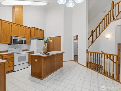 a kitchen with stainless steel appliances granite countertop a stove top oven a sink dishwasher and a refrigerator with wooden cabinets