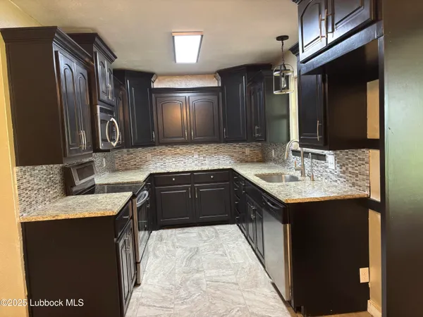 a kitchen with stainless steel appliances granite countertop wooden cabinets a refrigerator and a sink