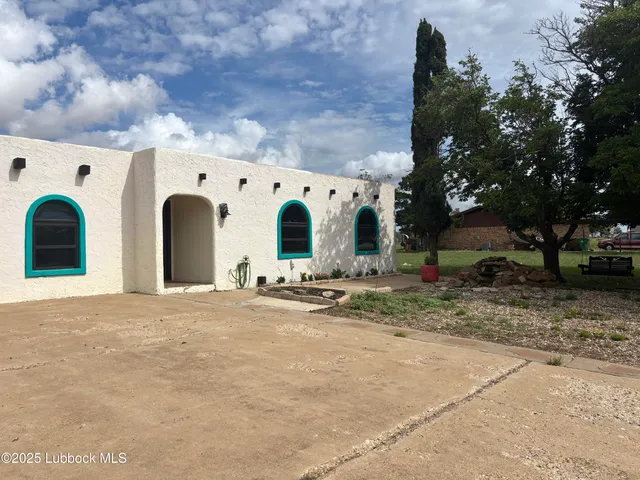 a view of a white house with a large space and large trees