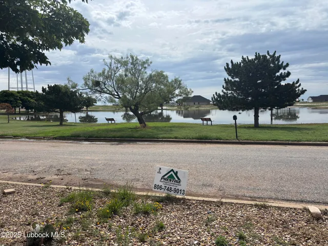 a lake view with a big yard and a fountain