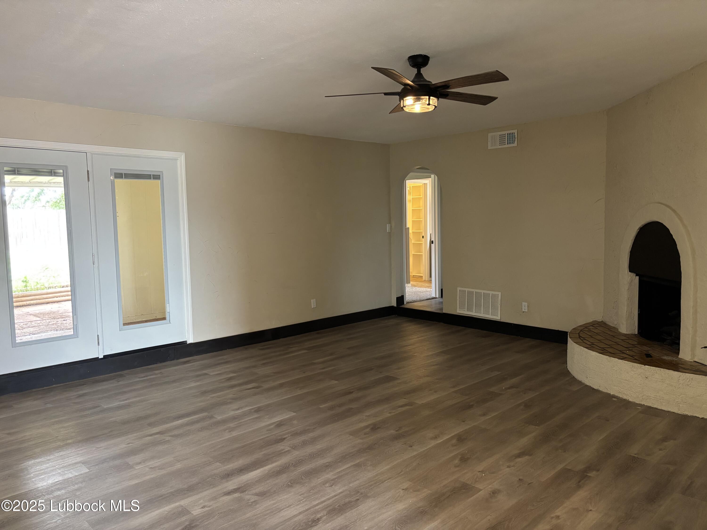 5 Parklane Drive Ransom Canyon, TX 79366 - Photo 8 of 30 an empty room with wooden floor chandelier fan and windows