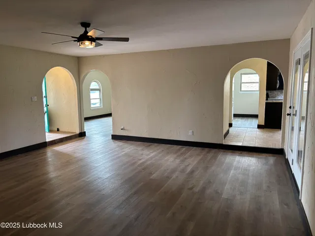 a view of empty room with wooden floor and fan