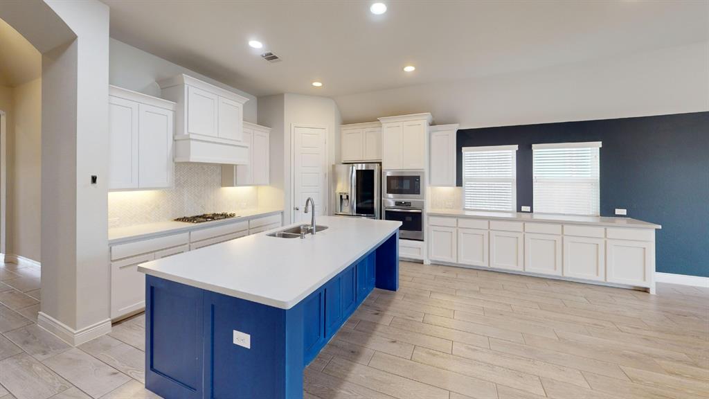 1516 Twistleaf Road Flower Mound, TX 76226 - Photo 4 of 22 a kitchen with kitchen island sink stove and white cabinets