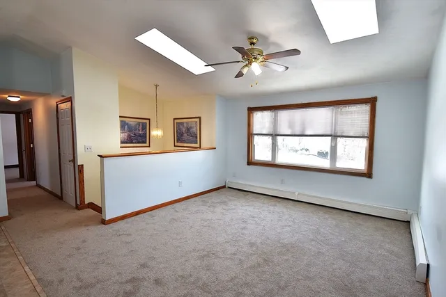 an empty room with windows and chandelier fan